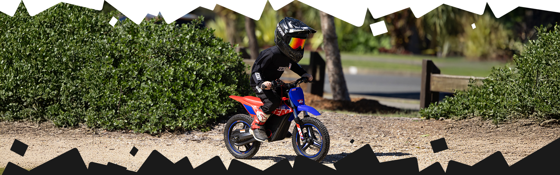Child on a small bike in a park-like setting with trees and grass.