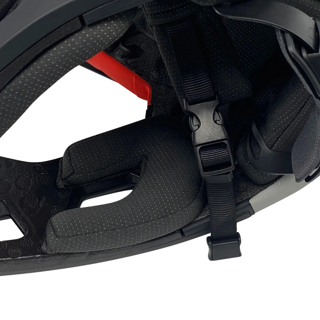 Close-up of a black bicycle helmet interior showing the padded chin pad, adjustable strap, buckle, and textured inner lining.